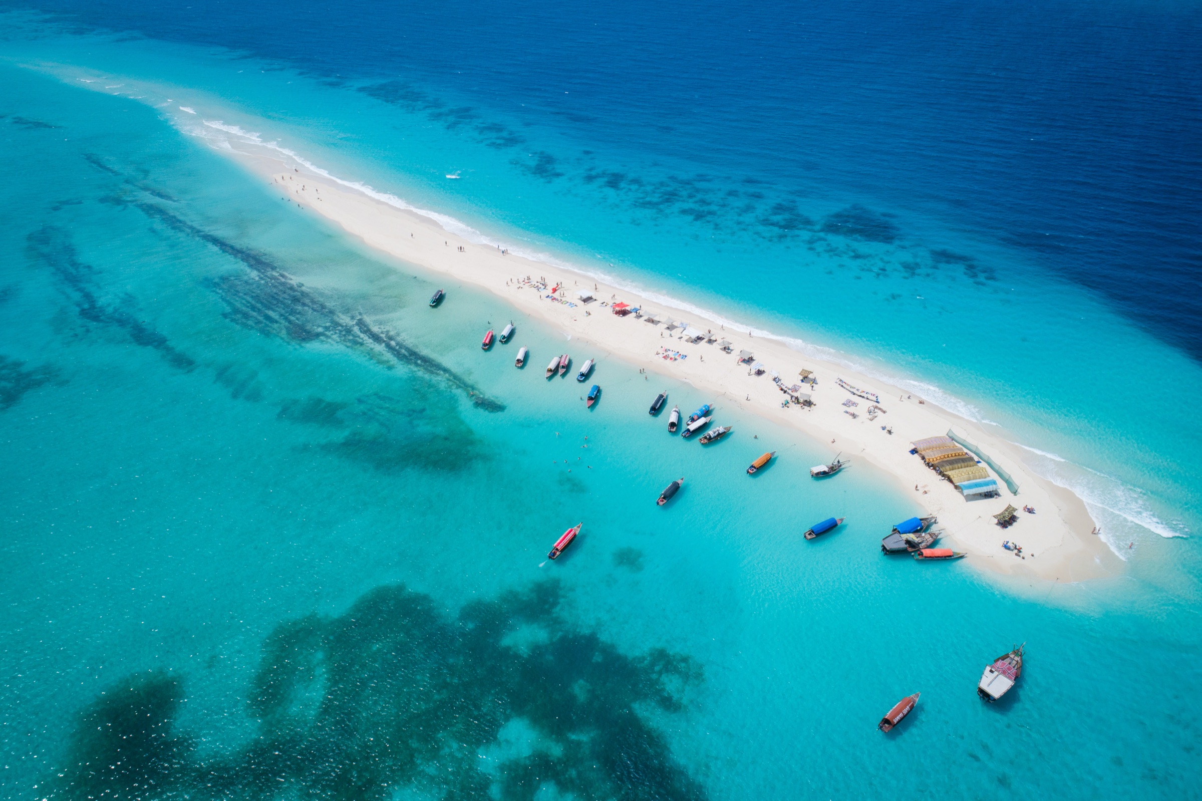 An aerial view of a Zanzibar sandbar, turquoise water and a long white beach.