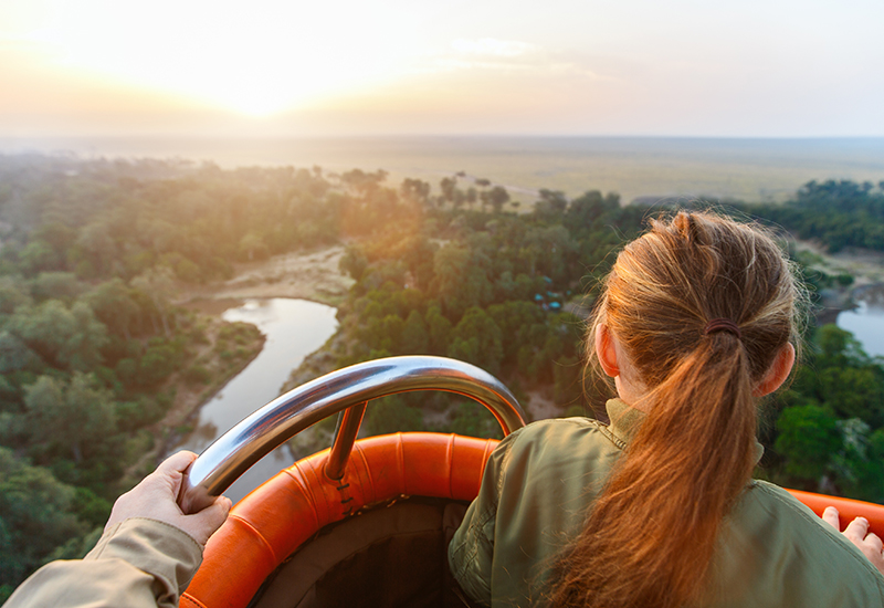 girl stands in hot air balloon safari over kenya